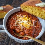 bowl of chili with corn bread on table