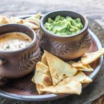 Bowls of queso & guacamole on table