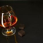 Hennessy Cognac glass and chocolate on black background