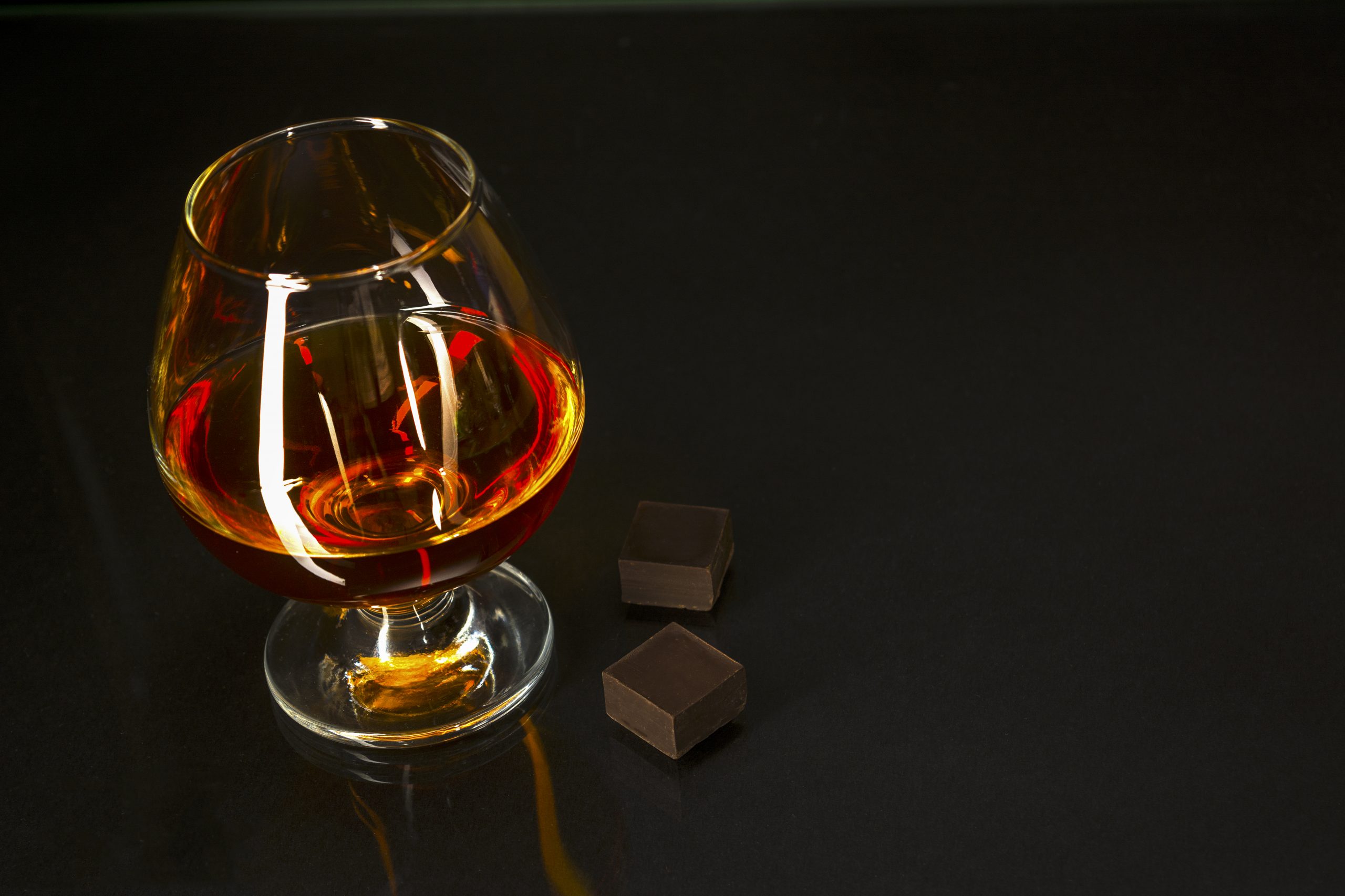 Hennessy Cognac glass and chocolate on black background