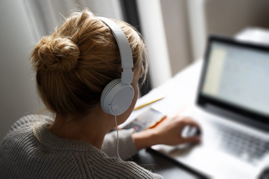 woman listening to audible while reading laptop