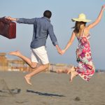 couple on beach with travel bag buying vacation property in mexico