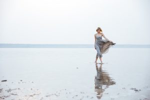 woman in long dress walking on the beach at beach wedding