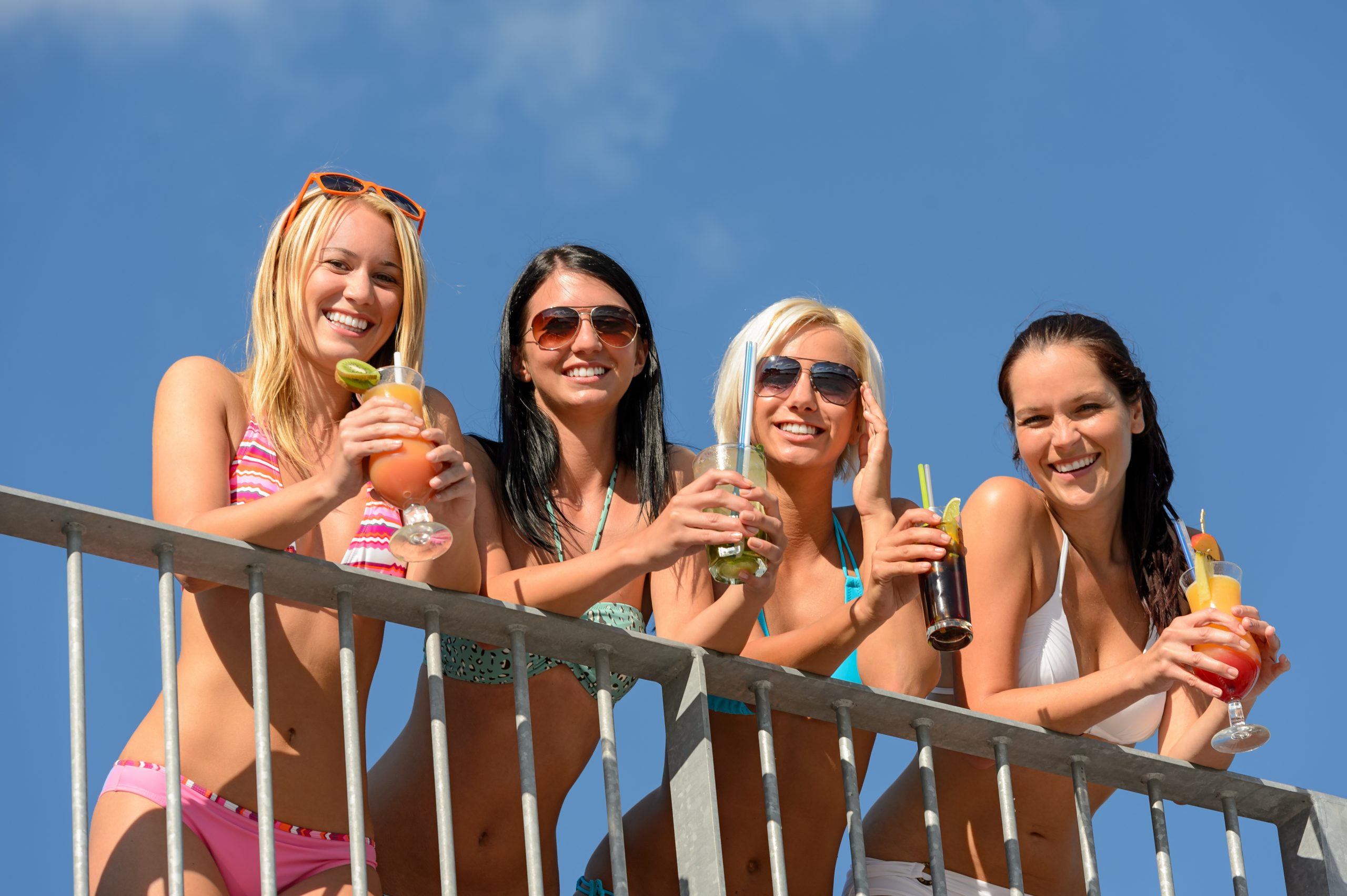 women in bikinis smiling with mexican cocktails all above the legal drinking age in mexico