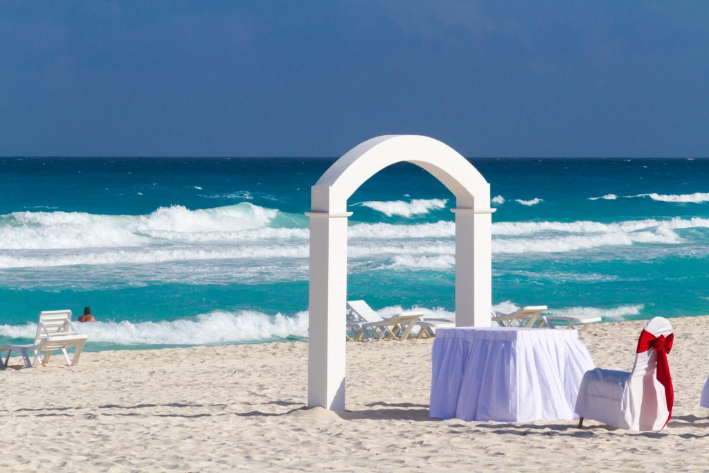 mexican beach wedding reception chairs with red and white ribbons
