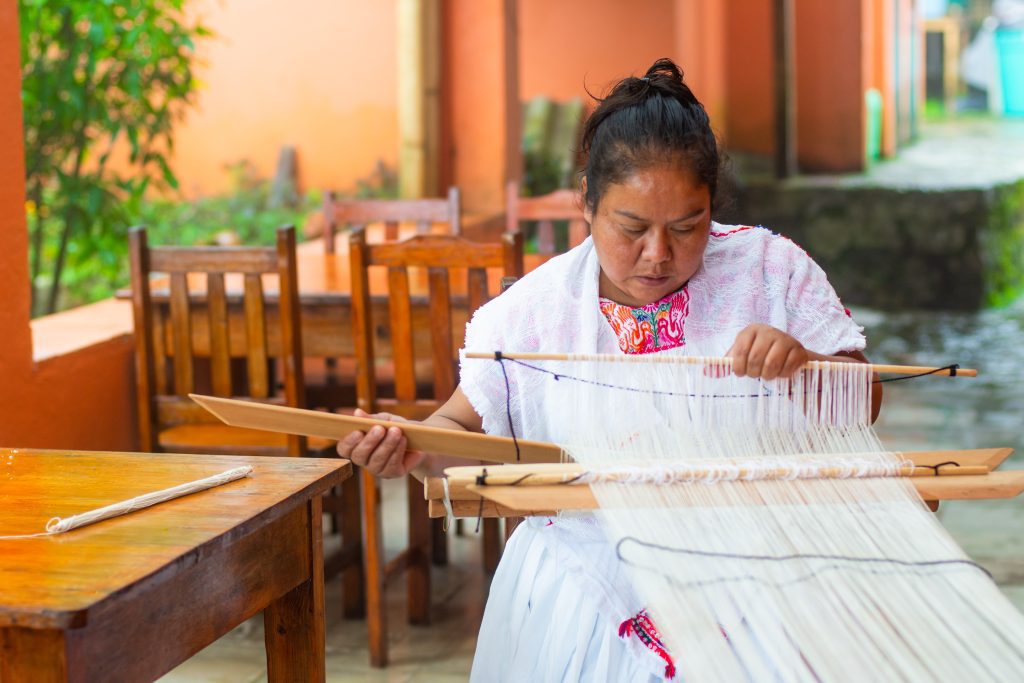 mexican woman weaving tapestry on loom